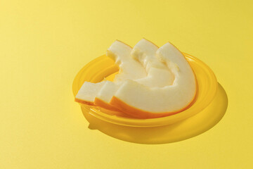 Fresh Yellow Melon Slices on Vibrant Yellow Plate in Minimalist Setting