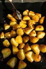 Roasted sliced potatoes straight out of the oven and serving spoon.