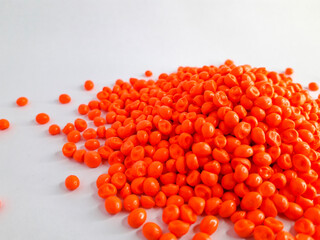 Neon orange masterbatch granules on white background. Color pigment carrier polymer in plastic industry
