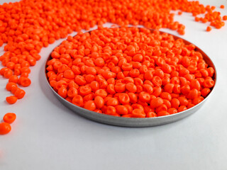 Neon orange masterbatch granules on white background. Color pigment carrier polymer in plastic industry