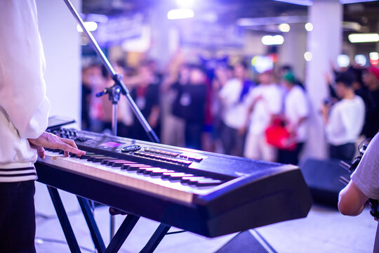 POV of a musician playing keyboard on stage looking out at a large, cheering audience inside an auditorium theater.