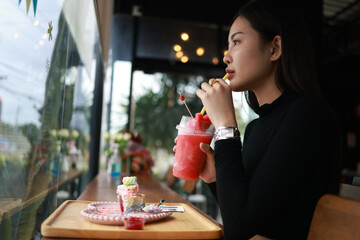 A beautiful young Asian woman drinking watermelon juice while sitting in the  cafe