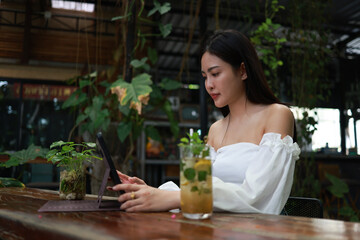 Captivating young Asian professional seamlessly manages her business, indulges in online shopping, transfers money, tends to financial matters, and conducts internet banking from the comfort of a bust
