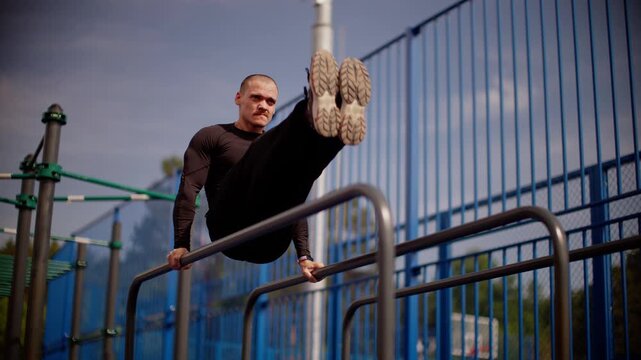 Slow-motion calisthenics routine on outdoor parallel bars