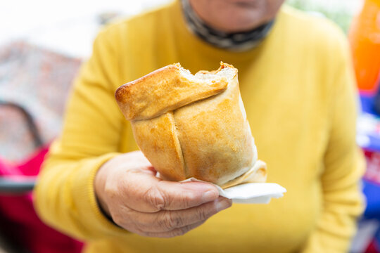 Woman holding a Chilean meat empanada during Chile's national holidays, which are celebrated on September 18th throughout the country
