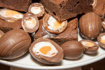 A plate of delicious chocolate cream easter egg brownies, chocolate easter eggs treats on a wooden kitchen table