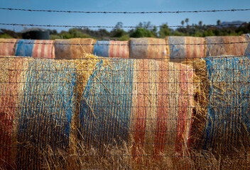 Close up of bales of hay wrapped in American flags behind barbed a wire fence in a field © F Armstrong Photo