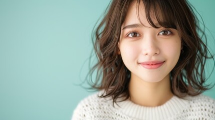 Fototapeta premium Smiling woman in white sweater against mint green background