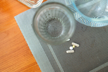 serene moment of health and self-care, featuring pills beside a glass of water on a dining table, symbolizing the importance of medication and hydration in daily life