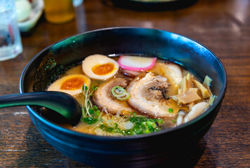 Japanese noodle soup ramen with egg and pork in black ramen bowl for Japanese food style.