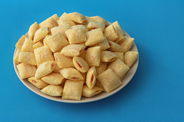 Cookies - corn cushions with strawberry flavored filling on a plate on a blue background