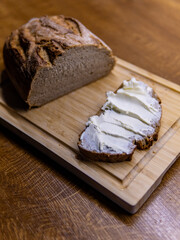 black bread on a wooden board, sliced pieces spread with butter