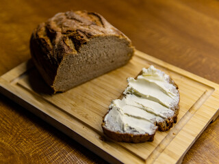 black bread on a wooden board, sliced pieces spread with butter