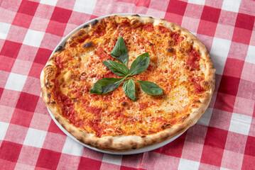 Margherita italian pizza with: tomato, basil and mozzarella cheese, on table with checkered tablecloth