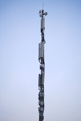 Obraz premium Telecommunication tower with multiple antennas against a clear sky. Vertical shot of a cellular tower used for wireless communication. Technology and infrastructure concept.