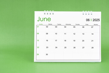 June 2025 desk calendar isolated in green background.