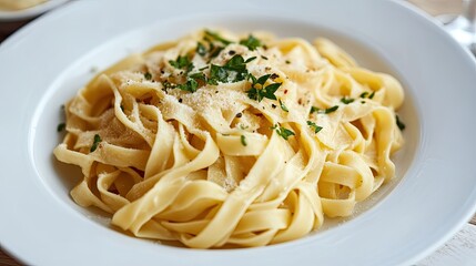 Elegant plate of tagliatelle pasta with a light, delicate sauce and a garnish of fresh herbs.