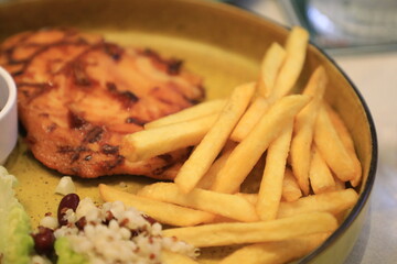 Grilled chicken breast served with crispy French fries, a fresh salad, and a side of tangy barbecue sauce is perfect for food lovers and culinary enthusiasts.