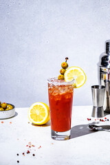 Tomato  alcoholic cocktail drink, variation of Bloody Mary with juice, vodka, lemon, celery, spicy sauce and ice. Gray background, hard light