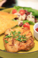 Grilled chicken breast served with crispy French fries, a fresh salad, and a side of tangy barbecue sauce is perfect for food lovers and culinary enthusiasts.