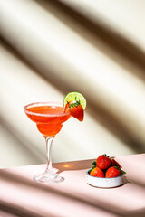 Strawberry summer red cocktail drink with tequila, limу juice, liqueur, berries and ice in glass. Beige background., hard light