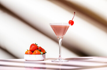 Delicious summer cocktail with vodka, liqueur, cream, strawberries and ice  with cocktail cherry. Beige background, hard light