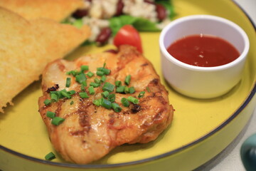 Grilled chicken breast served with crispy French fries, a fresh salad, and a side of tangy barbecue sauce is perfect for food lovers and culinary enthusiasts.