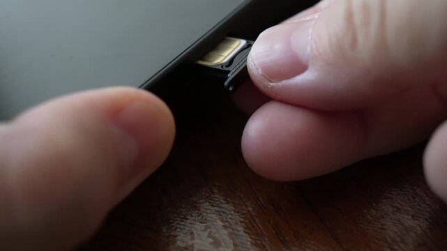 Person inserting a sim card into back of mobile phone, Sim card in tray being inserted into phone, closeup