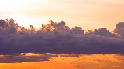 Dark rain clouds on dramatic orange sunset sky background in the evening 