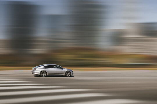 Car driving, fast motion on highway. Dynamic running car on road, blurred city background. Side view