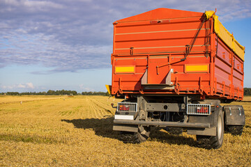 Tractor in the Stubble Field. Tractor Trailer in Wheat Field. Agricultural Tractor Trailer. Perspective. Copy Space.