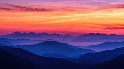 Obraz premium Sunset over a mountain range, with the sky painted in shades of orange, pink, and purple, and the mountains silhouetted against it.