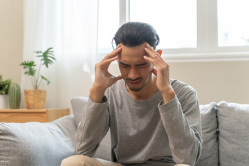 Guy have headache and dizzy sitting on sofa at home