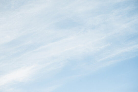 Milky sky with clouds resembling mist. Soft heaven texture of the sky. Hazy, foglike clouds providing a dreamy, heavenly atmosphere. Blue sky background. Bright clodus pattern.