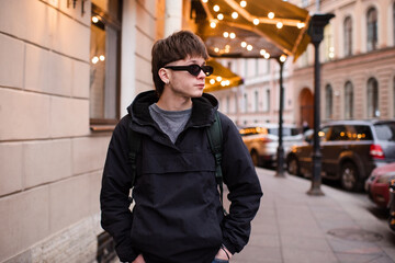 Stylish handsome young man 22-24 year old walking on city street over Christmas glowing lights. Winter holiday season. © morrowlight