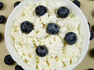     Fresh cottage cheese with blueberries is in a white bowl on the table, healthy food with...