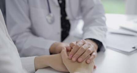 Obraz premium Doctor and a patient. The female physician, wearing a white medical coat over a dark blue dotted blouse, is reassuring a woman during a consultation in the clinic. Medicine concept