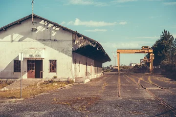 Fototapeten Verlassene Gebäude Abandoned industrial building with a weathered facade and an old rail track in Leiria, Portugal. The site reflects a nostalgic, post-industrial atmosphere  © skyNext