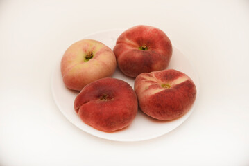 Flat peaches on a white plate. Delicious yellow peaches.