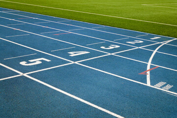 Treadmill with blue color and white numbers on it in the vohle of a large soccer field with green artificial grass.