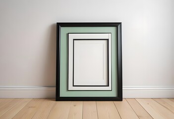 A black picture frame on a wooden floor against a white wall