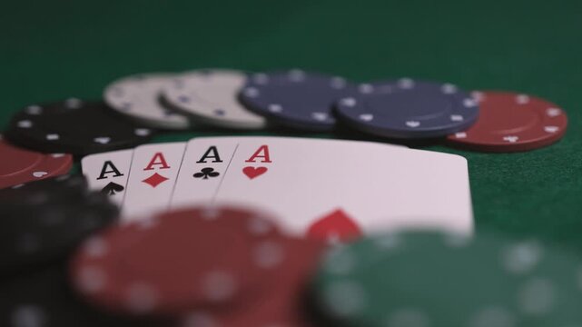 Close up of poker chips and playing cards of four aces on a green table top with smooth sliding and panning motion
