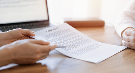 Naklejka premium Businesswoman lawyer pointing into contract special points admitting something for colleague or client at the wooden desk in office. Business people teamwork and partnership, meeting concept