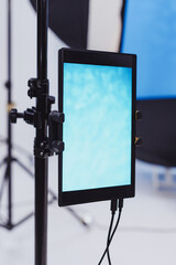 A vibrant blue display illuminates an artistic studio filled with soft lighting and backdrop equipment