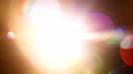Colourful rays of light and glows and lens flares on a dark background.