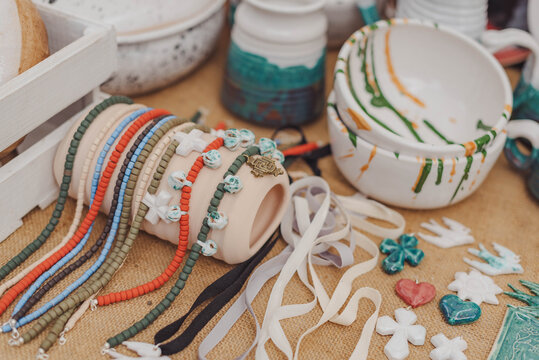 Colorful handmade pottery and vibrant jewelry displayed at a craft fair in the afternoon sun