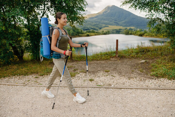 A young woman hikes enthusiastically through a beautiful natural landscape, with a backpack