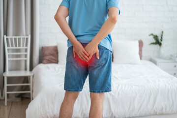 Hemorrhoidal pain, man suffering from hemorrhoids at home