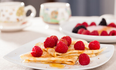 Breakfast of pancakes with fresh raspberries on table