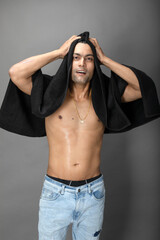 Naklejka premium Cropped view of a young shirtless athlete with black towel after shower, bath or sauna. Indian bodybuilder with happy, mischievous facial expressions posing for camera